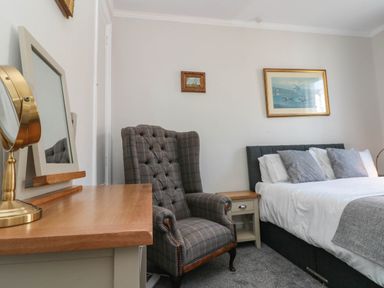 A bedroom with a desk mirror armchair bed and framed pictures on the wall at Rydal Cottage in Scarborough