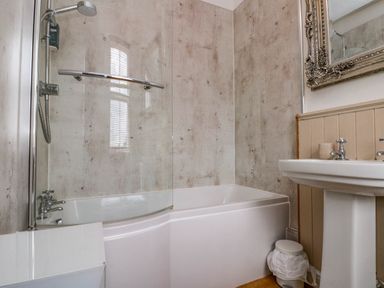 A bathroom with a bathtub shower combination pedestal sink and a mirror at Rydal Cottage in Scarborough