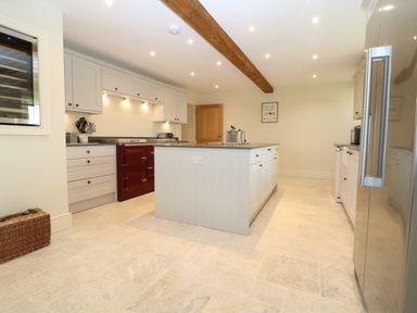A kitchen with a central island white cabinets a stainless steel refrigerator and a red stove at Morgans Farmhouse in Bampton Oxfordshire