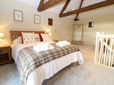 A bedroom with a double bed pillows bedside tables lamps and a wooden clothes rack at Morgans Farmhouse in Bampton Oxfordshire