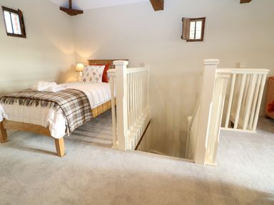 A bedroom with a single bed and a staircase with white railing at Morgans Farmhouse in Bampton Oxfordshire