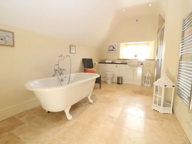 A bathroom with a freestanding bathtub a chair a toilet a sink and decorative lanterns at Morgans Farmhouse in Bampton Oxfordshire