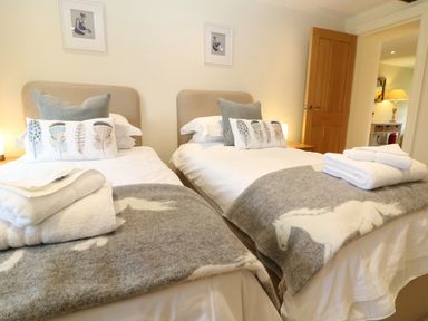 A bedroom with two single beds with white bedding and grey horse blankets at Morgans Farmhouse in Bampton Oxfordshire