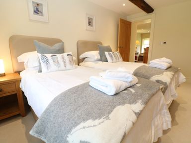 A bedroom with two single beds bedside table and door at Morgans Farmhouse in Bampton Oxfordshire