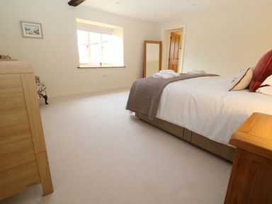 A bedroom with a bed folded towels on the blanket a window a wooden door and a wooden dresser at Morgans Farmhouse in Bampton Oxfordshire