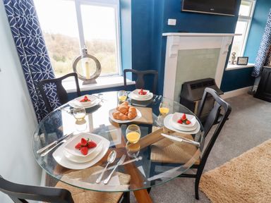 A dining area with a glass table set for four with croissants strawberries and orange juice at The Stable in Lydney