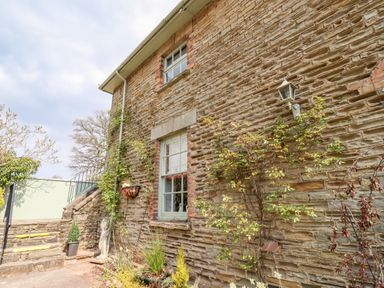Stone exterior wall of a house with windows plants and stairs leading to a gate at The Stable in Lydney