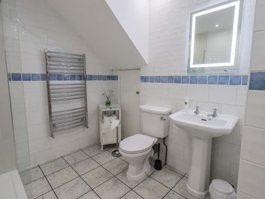 A bathroom with a toilet, sink, and mirror at Red Screes in Ambleside