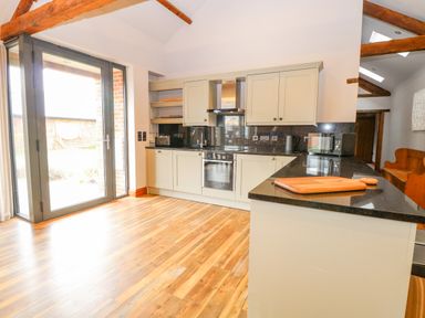 A kitchen with wooden floor and beige cabinets and doors with glass panels at Shorthorn Barn in Attlebridge near Taverham