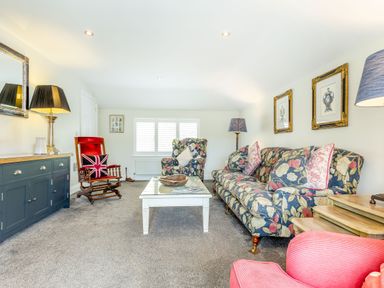 A living room with floral upholstered sofa and armchair a wooden rocking chair and coffee table at Armando in Devoran Cornwall