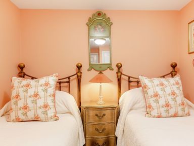 A bedroom with two single beds with patterned pillows and a nightstand with a lamp and mirror at Armando in Devoran Cornwall