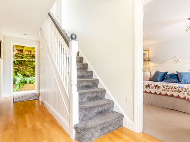 A hallway with carpeted stairs on the left and a bedroom with a bed and pillows on the right at Armando in Devoran Cornwall