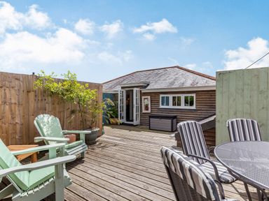 A wooden deck with outdoor furniture and potted plants at Armando in Devoran Cornwall