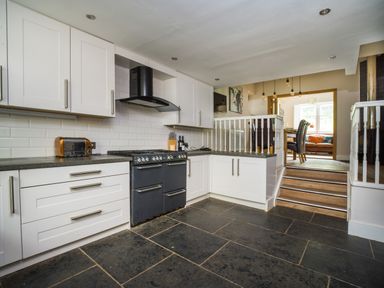 A kitchen with white cabinets a black stove and black floor tiles at Fellside Lodge in Bowness-On-Windermere