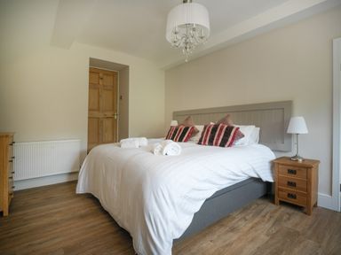 A bedroom with a double bed wooden bedside tables and a wooden door at Fellside Lodge in Bowness-On-Windermere