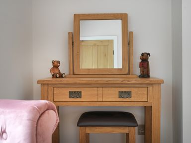 A wooden dressing table with a mirror and two wooden animal figurines in a room at Fellside Lodge in Bowness-On-Windermere