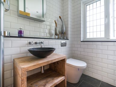 A bathroom with a wooden vanity and black vessel sink toilet and a window at Fellside Lodge in Bowness-On-Windermere