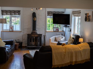 A living room with leather sofas a wood stove and a wall-mounted TV at The Old Post Office in Llandrindod Wells