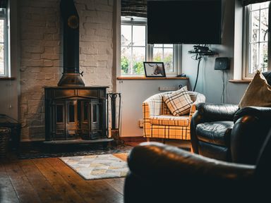 A living room with a wood stove and armchairs at The Old Post Office in Llandrindod Wells