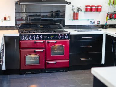 A kitchen with a red and black stove oven and black cabinets at The Old Post Office in Llandrindod Wells