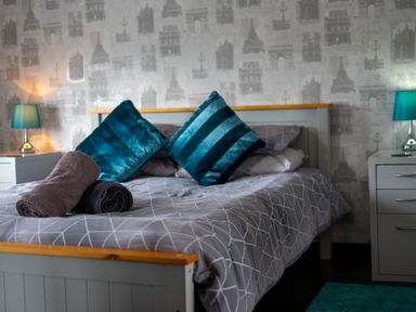 A bedroom with a bed with pillows and rolled towels and bedside tables with lamps at The Old Post Office in Llandrindod Wells