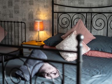 A bedroom with a metal bed frame pillows a bedside table and a lit lamp at The Old Post Office in Llandrindod Wells