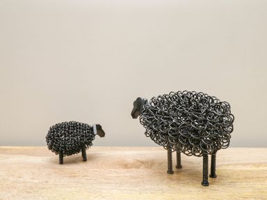 A small and a large black wire sculpture of sheep on a wooden surface at Netherbeck in Ambleside