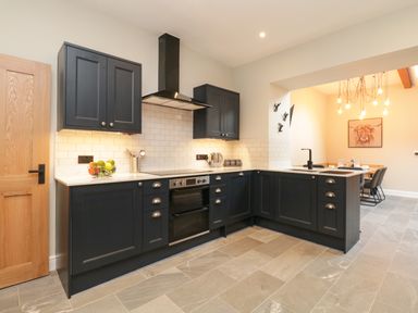A kitchen with black cabinets white countertops and tiled backsplash at Netherbeck Ambleside