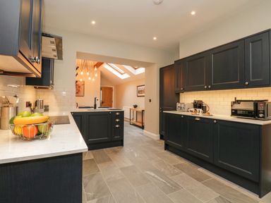 A kitchen with dark cabinets white countertops a fruit basket and appliances at Netherbeck in Ambleside
