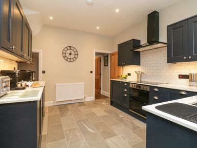 A kitchen with dark cabinets tiled floor and a wall clock at Netherbeck Ambleside