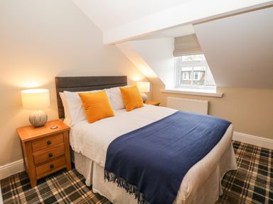A bedroom with a double bed two wooden bedside tables with lamps and a window at Netherbeck in Ambleside