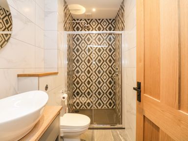 A bathroom with a toilet sink and shower with geometric tile at Netherbeck in Ambleside