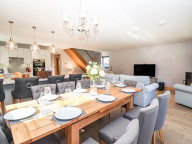A dining table set with plates and wine glasses in an open plan kitchen and living room at Lake View Lodge in Thorpe-On-The-Hill