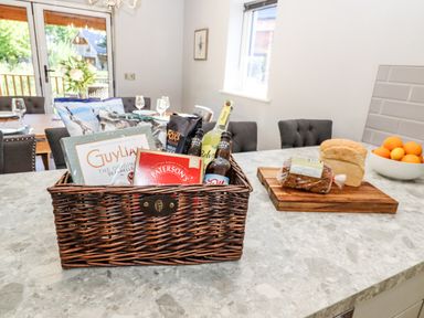 A kitchen countertop with a basket of snacks bottles and two loaves of bread on a cutting board in a dining area at Lake View Lodge in Thorpe-On-The-Hill