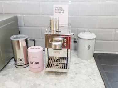 A kitchen countertop with a coffee grinder machine milk frother a canister of coffee pods and a white canister at Lake View Lodge in Thorpe-On-The-Hill