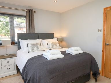 A bedroom with a double bed black blanket white towels bedside tables and lamps at Lake View Lodge in Thorpe-On-The-Hill