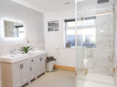 A bathroom with double sinks, a toilet, a walk-in shower, and a window at Lake View Lodge in Thorpe-On-The-Hill