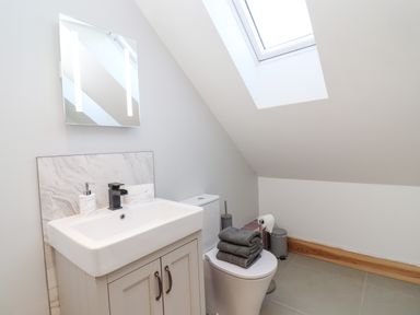 A bathroom with a sink vanity mirror toilet window and folded towels on the toilet seat at Lake View Lodge in Thorpe-On-The-Hill