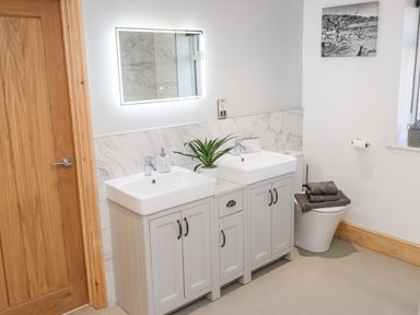 A bathroom with double sinks a plant a mirror and a toilet with towels at Lake View Lodge in Thorpe-On-The-Hill