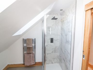 A bathroom with a glass shower enclosure marble tiled walls and a towel rack with towels at Lake View Lodge in Thorpe-On-The-Hill
