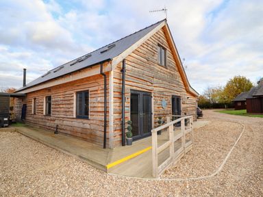 A wooden cabin with a small railing ramp and gravel driveway at Lake View Lodge in Thorpe-On-The-Hill