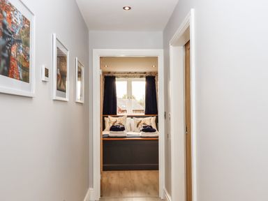 A hallway with pictures on the wall leading to a room with a window seat and cushions at Lake View Lodge in Thorpe-On-The-Hill