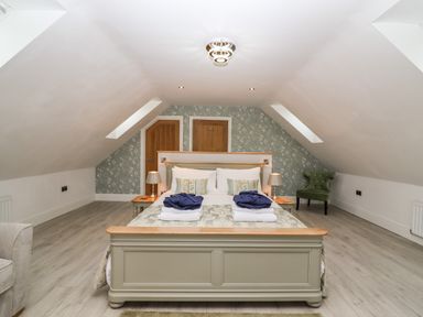 A bedroom with a bed and two bedside tables with lamps at Lake View Lodge in Thorpe-On-The-Hill