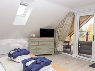 A bedroom with a dresser holding a television and flowers and folded bathrobes on a bed at Lake View Lodge in Thorpe-On-The-Hill