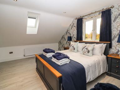 A bedroom with a double bed two bedside tables and a skylight window at Lake View Lodge in Thorpe-On-The-Hill