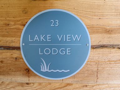 A blue circular sign with the text 23 Lake View Lodge on a wooden wall at Lake View Lodge in Thorpe-On-The-Hill