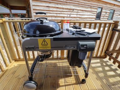 A barbecue grill with utensils and condiments on a wooden deck at Lake View Lodge in Thorpe-On-The-Hill