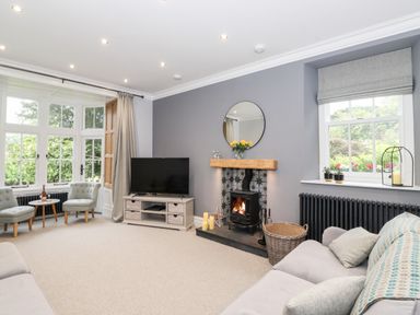 A living room with a fireplace TV and two chairs near windows at Eller Close House in Grasmere
