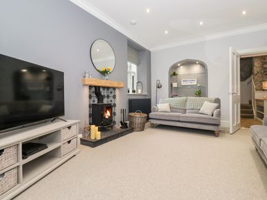 A living room with a television a wood burning stove a sofa and built in shelves at Eller Close House in Grasmere