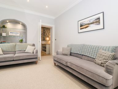 A sitting room with two sofas and a wall shelf with plants and books at Eller Close House in Grasmere